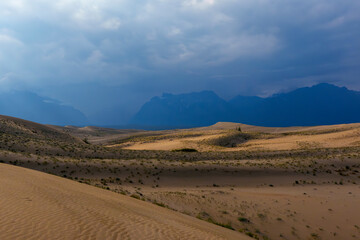 Dramatic desert dunes under sunbeams and cloudy sky