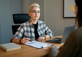 Fototapeta premium Young woman in a plaid shirt presenting a chart to a client in an office.