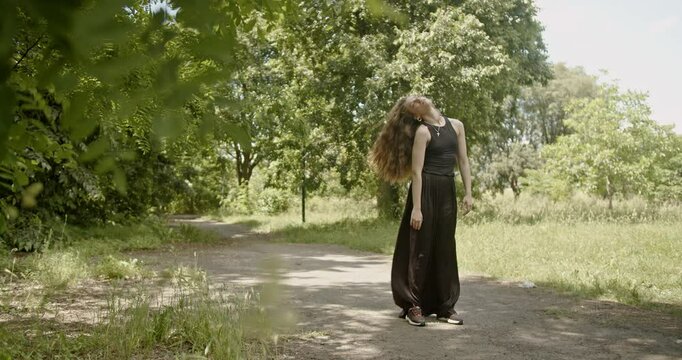 A young woman performs an interpretive dance in a peaceful forest setting.