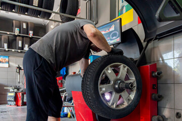 Car wheels maintenance. Expert tire repair and replacement at trusted vulcanization point with reliable service. Technical man balancing tires, maintenance and set the wheel center.