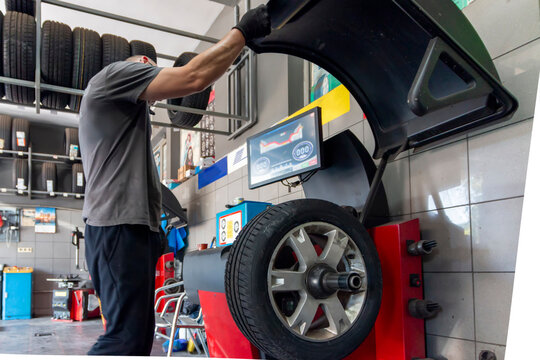 Car wheels maintenance. Expert tire repair and replacement at trusted vulcanization point with reliable service. Technical man balancing tires, maintenance and set the wheel center.