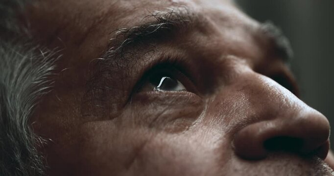 Elderly man close-up eyes gazing UPWARDS at sky. Older 70s person looking up with wrinkled expression in quiet contemplation