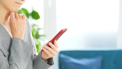 オフィスでスマホを使う女性ビジネスパーソン