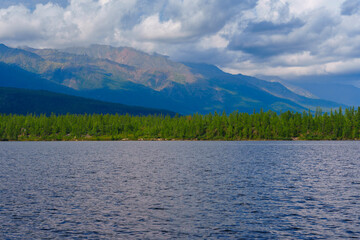 Lush green forest with mountain backdrop reflected in a calm lake