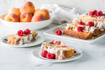 Servings of raspberry peach bread with the remaining loaf and peaches in behind.