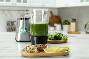 Modern blender with smoothie and ingredients on white marble table in kitchen