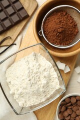 Flat lay composition with flour, chocolate and other ingredients for making dough on light table