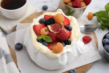 Pavlova cake (meringue dessert) with whipped cream, fresh berries, fig and mint on table, closeup