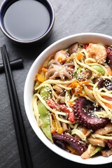 Stir-fry noodles with sea food served on grey textured table, flat lay