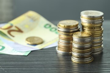 Stacks of coins and euro banknotes on grey textured table, closeup