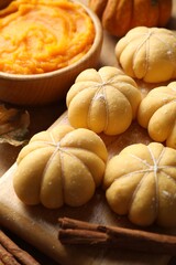 Raw pumpkin shaped buns and ingredients on table, closeup