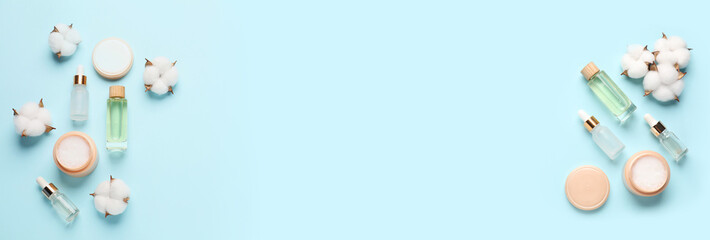 Cosmetic products and cotton flowers on light blue background, flat lay. Banner design with space for text