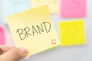 Hand holding BRAND text on sticky note. Build your Brand. Brand building, success, business