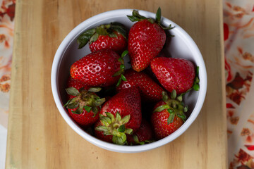 strawberries in a bowl on a wooden table