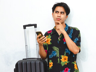 Portrait of a happy young Asian man wearing casual summer clothes, holding a mobile phone and...