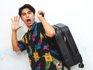 Young Asian man in summer casual wear carries a suitcase, running with a funny shocked expression. Isolated on a white background, perfect for travel themes. © Muhammad Alimaki