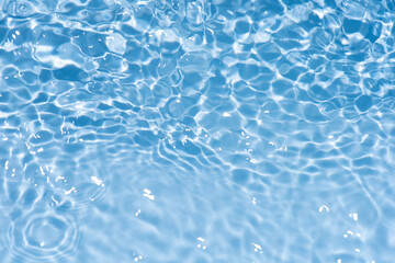 Fototapeta premium Blue water with ripples on the surface. Defocus blurred transparent blue colored clear calm water surface texture with splashes and bubbles. Water waves with shining pattern texture background.