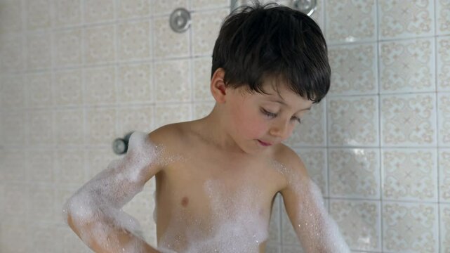 Young boy enjoying a bubble bath, covered in foam, making playful expressions, having fun, highlighting the joy and excitement of childhood moments in playful and lively scene