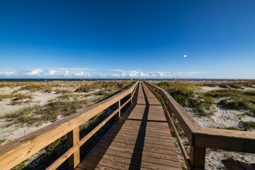 wooden pier at the Chatham Avenue Beach Access in Tybee Island, Georgia on a clear summer day with the ocean in the background