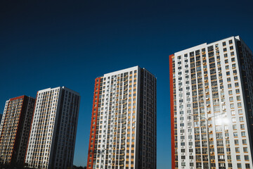 A splendid row of tall buildings rising majestically against a vivid blue sky, creating an...