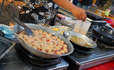 Close up of hands cooking dimsum in seblak. Sebalak is a typical Sundanese dish originating from the Parahyangan region with a savory and spicy taste.
