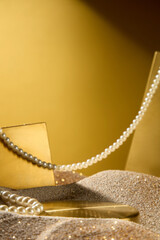 Creative photo of luxury concept from front view on gold background. Empty golden tray in the middle to display the product, a pearl string across in space