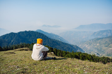 A young men  setting on a grass  Top of Raghupur Fort - Tirthan Valley himanchal pradesh india.