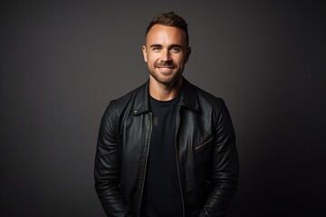 Obraz premium Portrait of a handsome young man in black leather jacket over grey background.