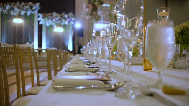 Rows of glasses and plates on the table. Elements of wedding. Many decorative candles for decorations on the table. 