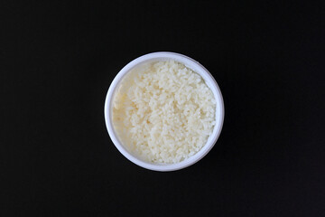 검은색 바탕에 둥근 플라스틱 포장 용기에 담긴 흰 쌀