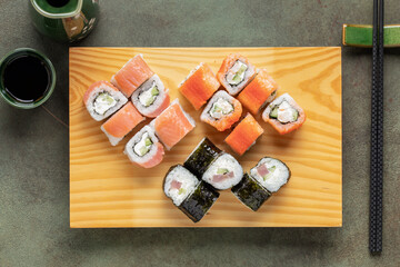 Set of sushi and maki with soy sauce on wooden plate . Top view