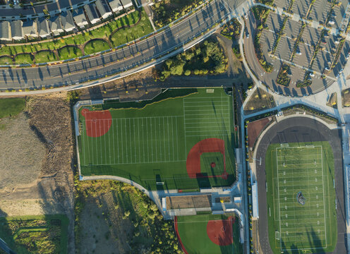 A baseball field with a red diamond and a football field with a white diamond
