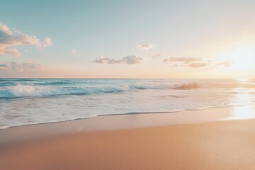 Soft, golden light bathes a sandy beach as the waves gently roll in.