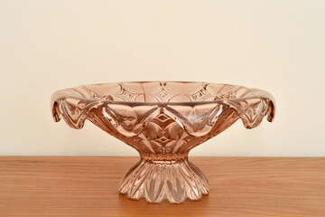 Vintage glass cake or fruit stand on the brown rustic wooden table. Close-up. Copy space.