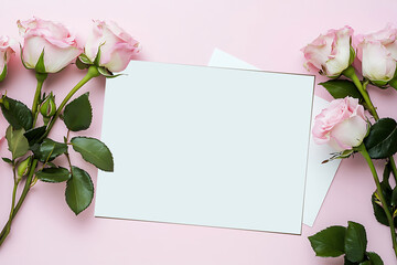 A blank white card with pink roses on the side, placed against a soft pastel background