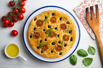 Italian focaccia with black olives and cherry tomatoes. Top view table with decorations.