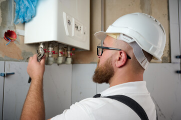 Plumber Install a Boiler. Professional engineer installing gas boiler at home and checking the...