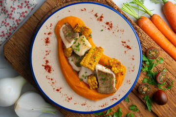 Delicious sole fish with carrot cream and corn. Top view table with  decorations.
