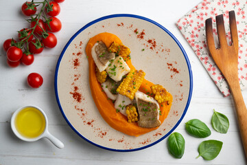 Delicious sole fish with carrot cream and corn. Top view table with  decorations.