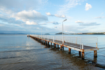 Fototapeta premium Wooden walking track built on the sea. Wooden bridge by the sea. Walking track with wooden floor and iron railings built in the sea. Quay walking area. Sea of ​​Erdek.