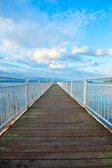 Obraz premium Wooden walking track built on the sea. Wooden bridge by the sea. Walking track with wooden floor and iron railings built in the sea. Quay walking area. Sea of ​​Erdek.