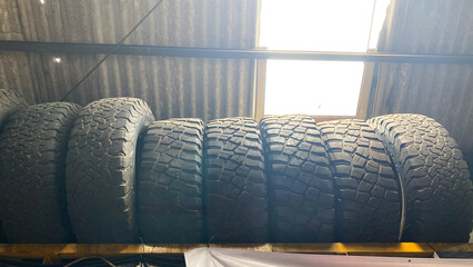 Off-road tires. used dirty tire line background. Used tires line the window of a repair shop .