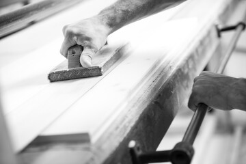 Black and white picture of Carpenter sanding wood using sanding