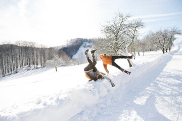 Friends having fun, jumping into high snow. First snowfall of the season.