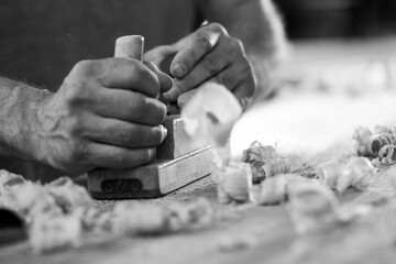 Black and white picture of Carpenter working wood using hand pla