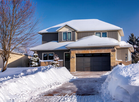Snowdrifts cleared from driveway of modern single family home 