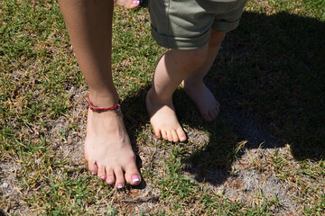 Mother and little daughter feet on the lawn. Mother's day concept