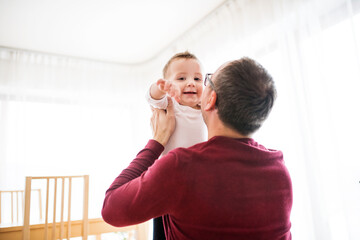 Father holding little son in the air, playing with him.