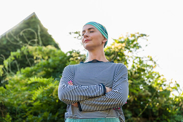 Beautiful young positive female cancer patient wearing headsacrf outdoors garden portrait. Mental...