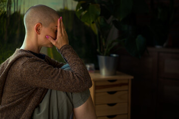 Young female cancer patient with head in hands indoors portrait. Mental health, emotional support,...